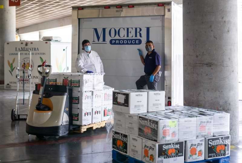 Chef and Moceri pose in front of the Moceri truck with boxes of produce